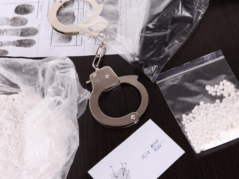 Handcuffs Next To Sealed Drugs