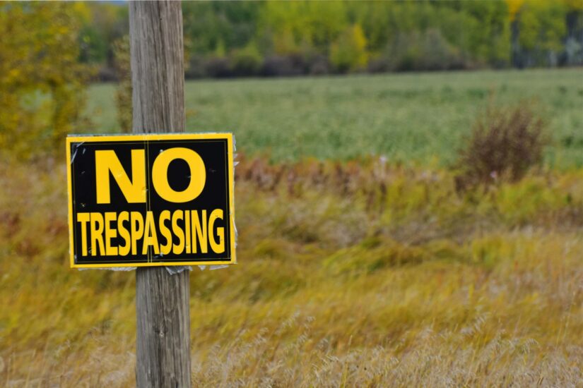 An image of an old no trespassing sign on a wooden post