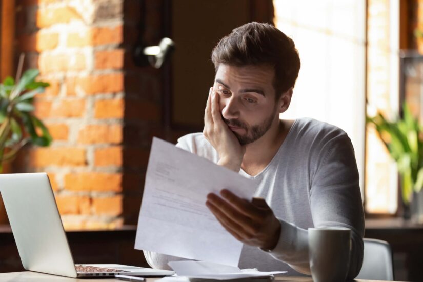 Confused frustrated young man reading letter receiving bad news